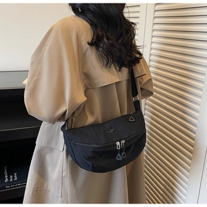 Rear view of a model wearing a black waterproof dumpling bag with adjustable strap
