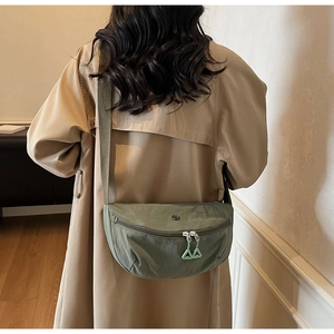 Detail of green dumpling crossbody bag on model back with adjustable strap and zip