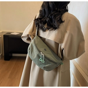 Detailed back view of model wearing a green nylon dumpling bag in a home setting