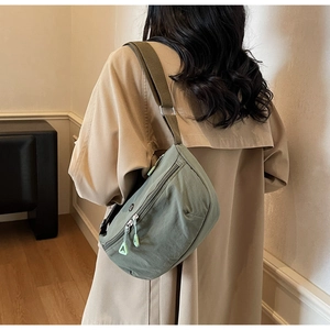 Detail of olive green nylon crescent bag with adjustable strap and zip pockets