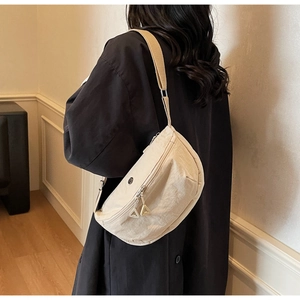 Detail view of cream nylon crossbody bag featuring textured fabric and metal logo detail