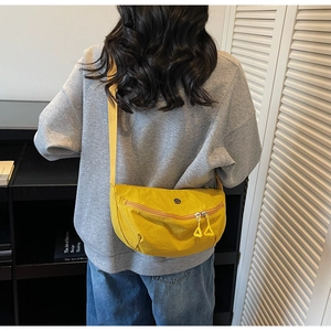 Detail of a bright yellow crescent crossbody bag with durable canvas texture and wide strap
