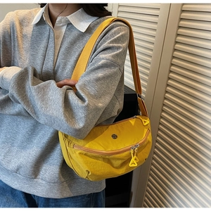 Detailed close-up of yellow nylon dumpling bag with dual zippers and woven shoulder strap