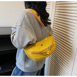 Detail of bright yellow nylon crossbody bag with dual zippers and wide shoulder strap