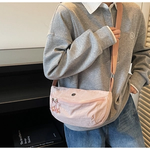 Detail of light pink dumpling bag with pleated texture and adjustable wide strap