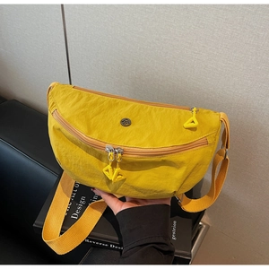 Detailed shot of yellow nylon dumpling bag with double zippers and black round logo