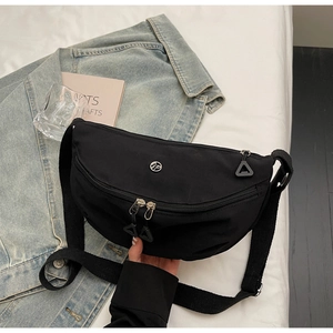 Detail of black nylon dumpling bag featuring metal logo and double zipper pullers