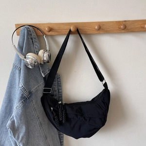 Detail of black nylon crescent bag with woven zipper pulls and silver hardware