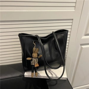 Retro schwarze Leder-Shopper mit stilvollem Hahnentritt-Hasenanhänger auf weißem Sockel