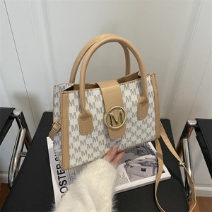 Minimalist white monogram tote bag with gold M buckle and adjustable crossbody strap