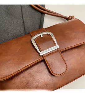 Detail of vintage brown leather bag with large silver rectangular buckle on textured wool