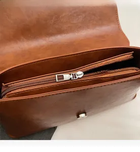 Detail shot of vintage brown PU leather bag showing internal compartment and smooth zipper