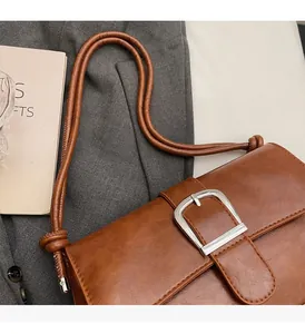 Detailed view of brown retro baguette bag with silver buckle and knotted shoulder strap