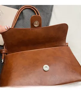 Detail of the vintage brown leather bag featuring a strong magnetic snap closure mechanism