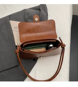 Internal view of brown leather shoulder bag showing spacious main pocket and zipper pouch