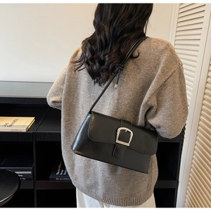 Chic black baguette bag with silver buckle worn over shoulder on a grey knit sweater