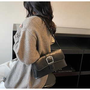 Detail shot of the black leather baguette bag featuring a bold silver buckle and slim strap