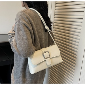 Detail of white baguette shoulder bag featuring silver square buckle and knotted strap