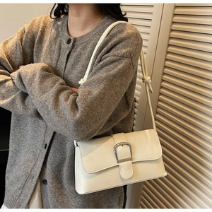 Detail view of a vintage creamy white baguette bag with a silver horseshoe buckle