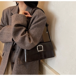 Detail view of deep brown baguette bag with silver buckle and sleek shoulder strap