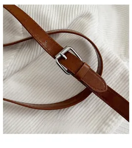 Detail of adjustable brown leather shoulder strap with silver buckle on tote bag