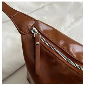 Detail of silver metal zipper and long leather puller on caramel tote bag with lychee texture