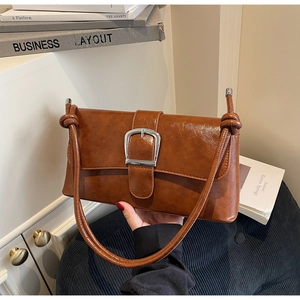 Detail of vintage brown baguette bag featuring a large silver buckle and glossy leather texture