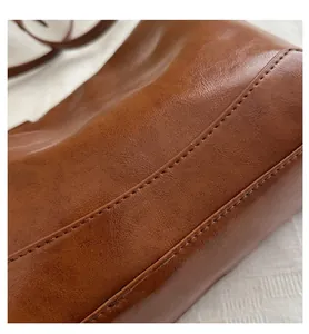 Close-up of brown oiled leather tote bag showing vintage texture and precise stitching