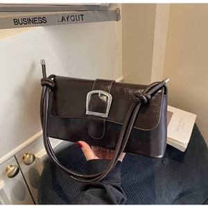 Close-up of deep brown glossy leather baguette bag with silver buckle and knotted straps