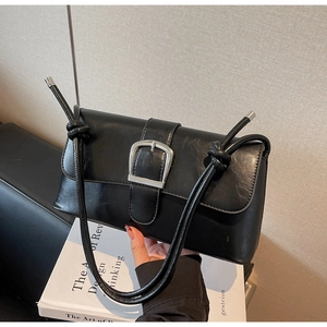 Detail of a black faux leather baguette bag with a large silver square metal buckle