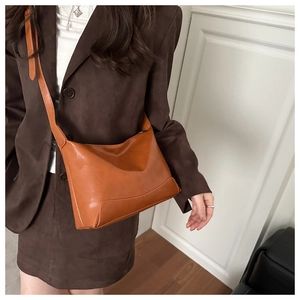 Detail of caramel glossy leather tote bag with elegant crescent shape and adjustable strap
