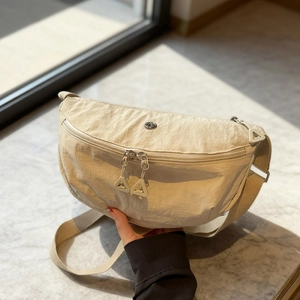 Beige nylon dumpling cross-body bag with dual zippers and minimalist logo detail