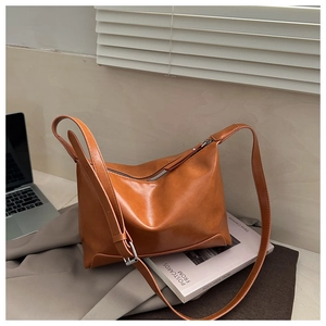 Detail of caramel leather tote with silver zipper and adjustable strap for daily commute