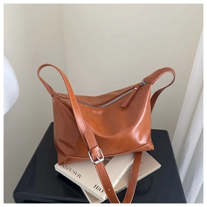 Detail of caramel tote bag with silver zipper and adjustable strap on lifestyle backdrop