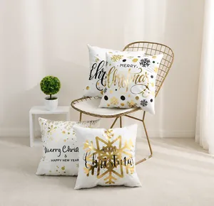 Dettaglio di federe natalizie bianche con scritte dorate Merry Christmas e fiocchi di neve