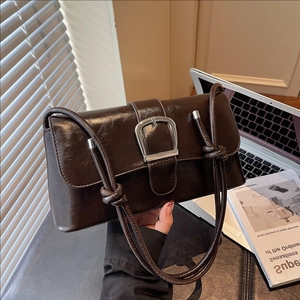 Deep brown chocolate bag with silver buckle and braided strap on an urban desk