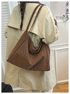 Detail of a large leopard print tote bag in dark brown suede being worn over the shoulder