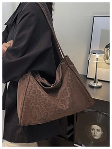 Leopard print tote bag styled with black coat in a modern minimalist home setting
