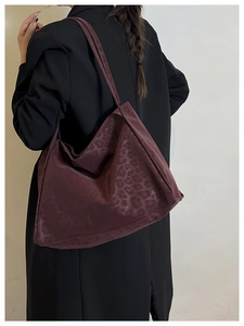 Detailed view of the oversized burgundy leopard print tote bag worn with a black blazer