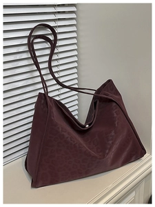 Detail of burgundy leopard print tote bag with smooth nylon texture and long shoulder strap