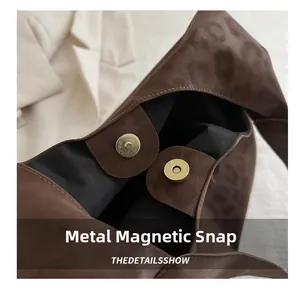 Detail of light gold magnetic clasp on brown leopard print suede tote with internal lining