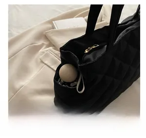 Detail of side pocket on black quilted tote bag holding a compact capsule umbrella