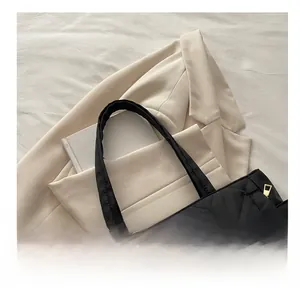 Detail of black quilted tote bag with diamond pattern and smooth golden zipper closure