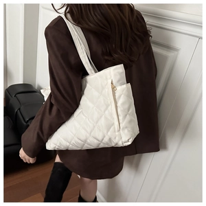 Quilted white nylon tote bag with side zipper detail shown on shoulder of a model