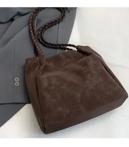 Detail of soft dark brown suede tote bag featuring woven straps and golden logo