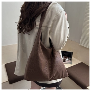 Detailed view of large leopard print tote bag with suede texture shown in a lifestyle scene