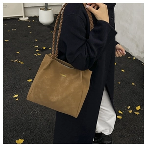 Detail of coffee suede tote bag featuring unique braided shoulder straps and gold logo