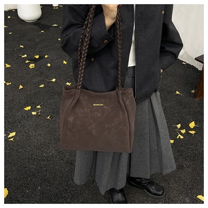 Detail of dark brown faux suede tote bag featuring woven straps and golden logo