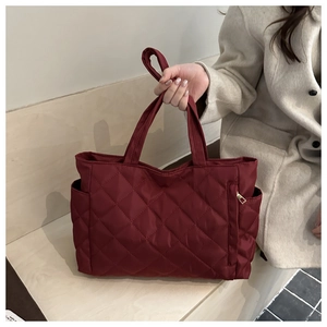 Detail of burgundy quilted tote bag featuring padded nylon texture and side zipper pocket