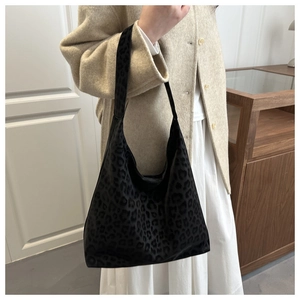 Detail of black leopard print tote bag styled with a beige cashmere coat and white skirt